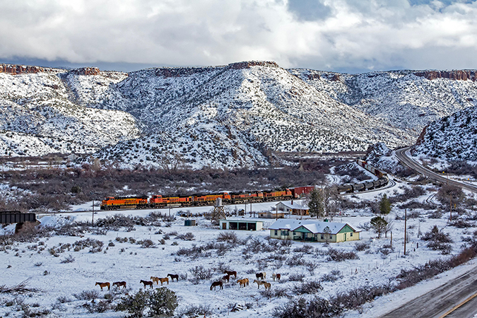 A mixed freight train passes grazing horses near Valentine, Arizona. A mixed freight train passes grazing horses near Valentine, Arizona.